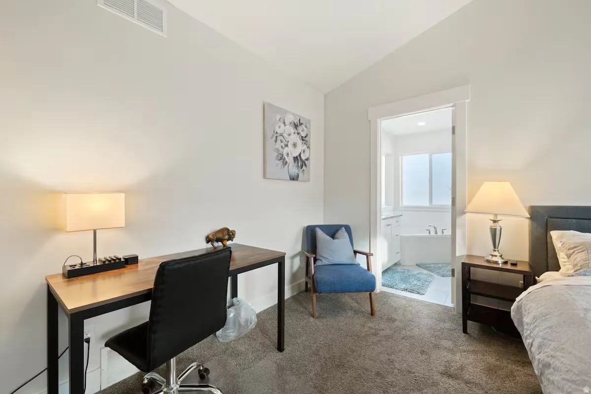 Carpeted bedroom with a built-in closet, a wood-finish desk, and a neutral wall color