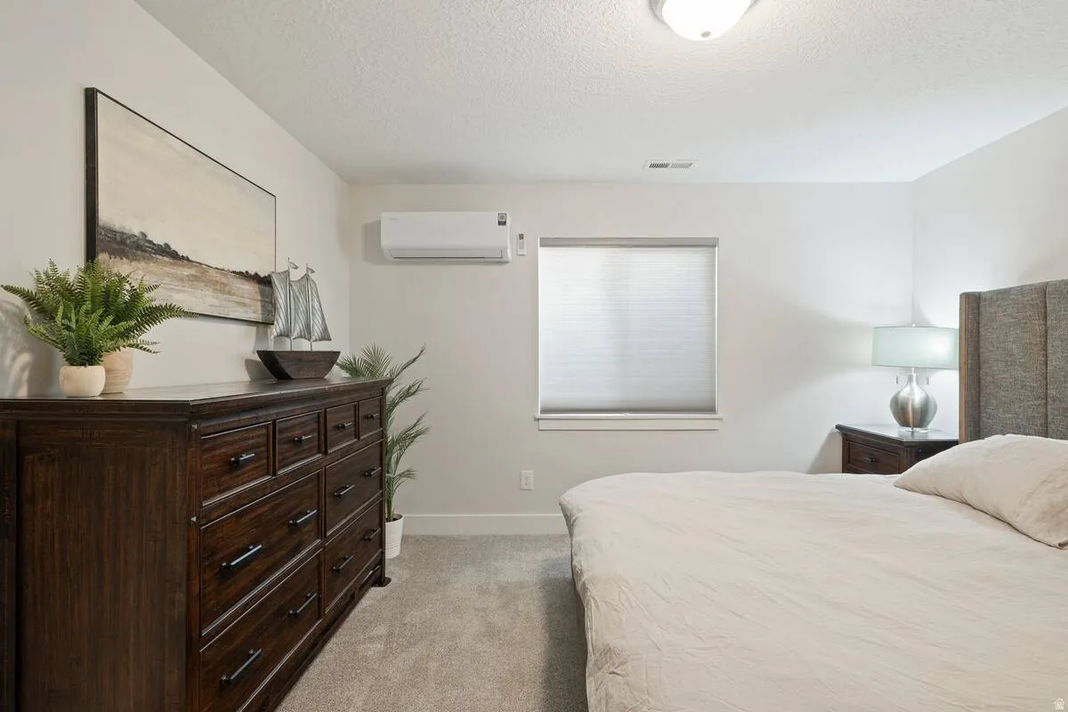 Recessed lighting, window with privacy blind, wall-mounted climate control unit, and plush carpet flooring