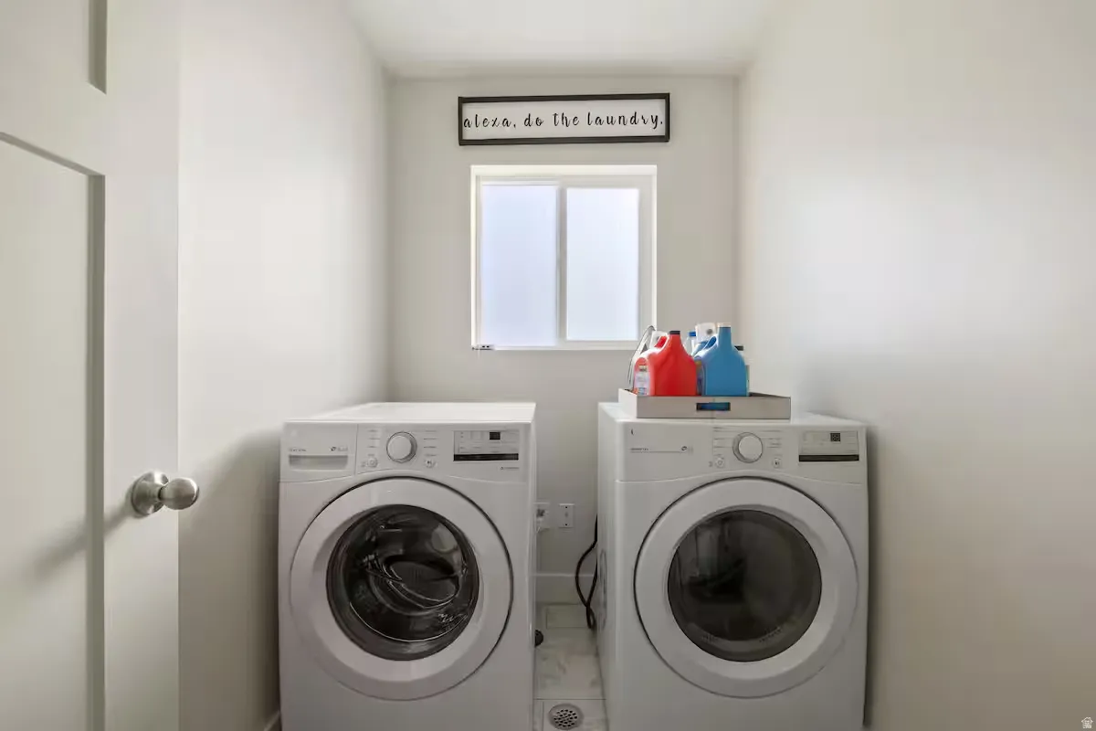 Dedicated laundry area featuring a window with privacy glass, a white front-loading washing machine, and a white front-loading dryer