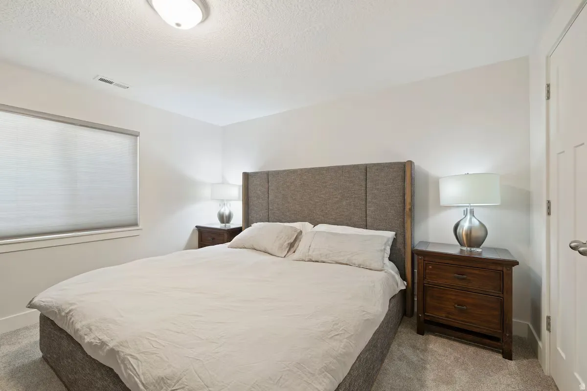 Window with cellular shade, recessed ceiling light, paneled door, and neutral-toned wall-to-wall carpeting