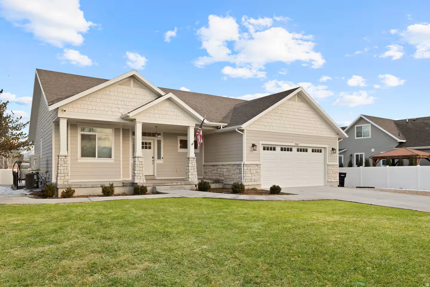 Exterior featuring light-toned siding, stone accents, and a covered entry