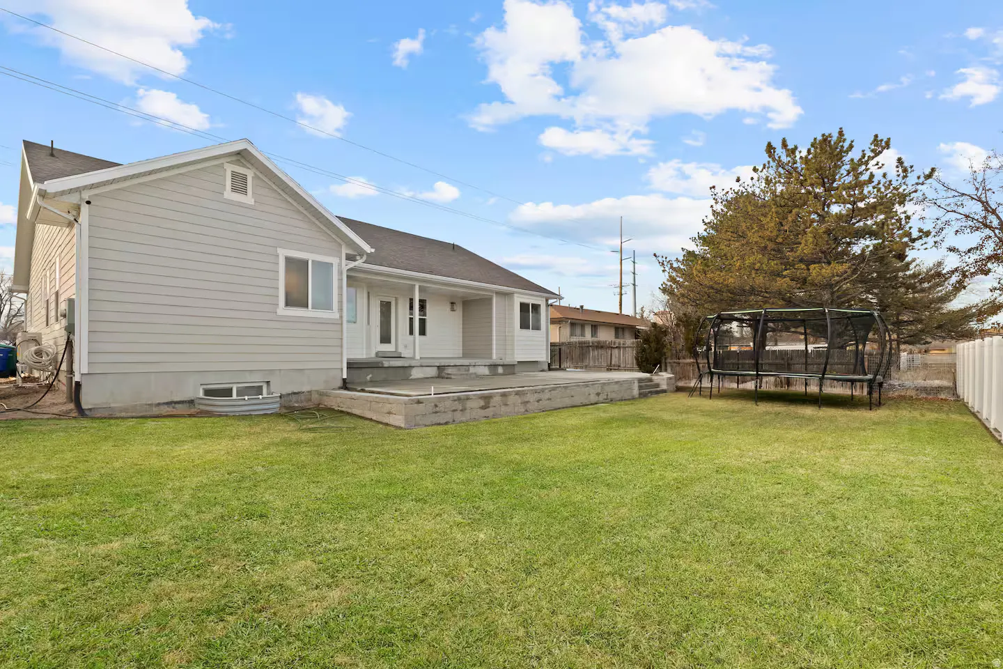 Expansive green lawn, concrete patio, and a light-colored siding exterior with white trim