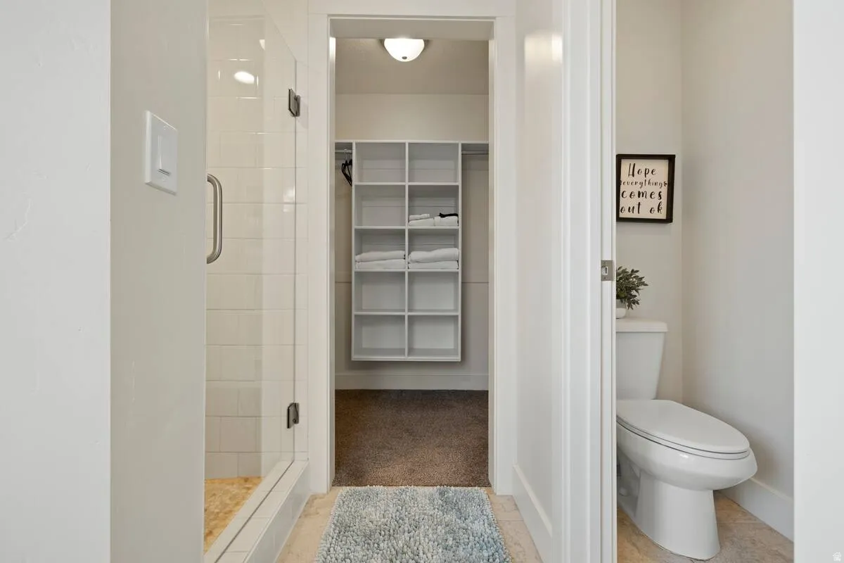 Glass-enclosed shower with subway tile surround and stone-look flooring