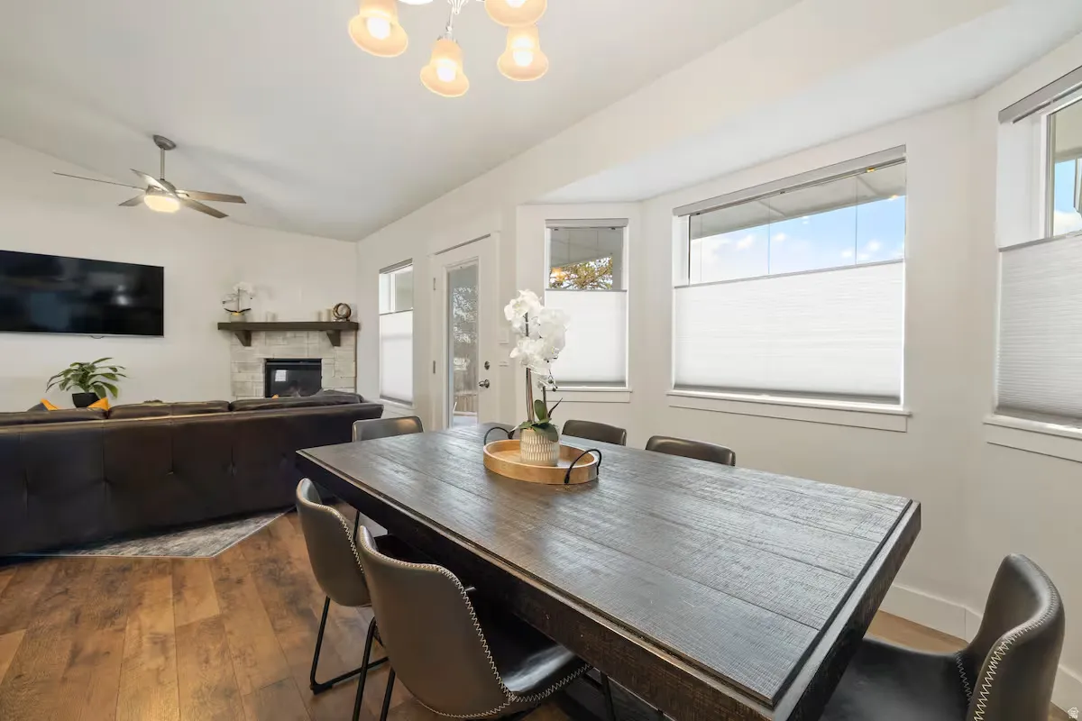 Wood-finish flooring throughout, a vaulted ceiling, and a fireplace with a stone surround