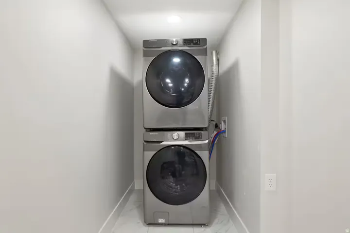 Laundry area featuring a stacked washer and dryer, recessed ceiling lighting, and tile flooring