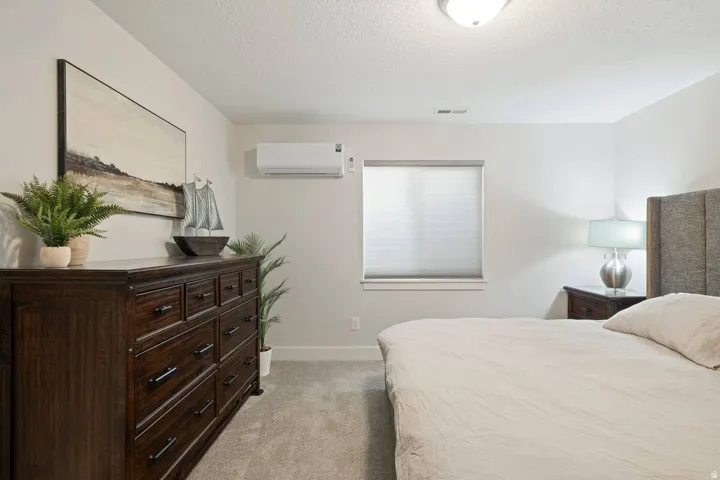Recessed lighting, window with privacy blind, wall-mounted climate control unit, and plush carpet flooring