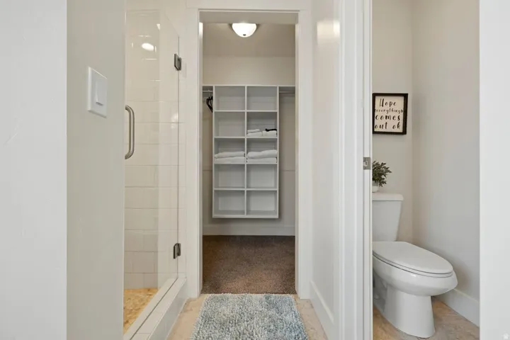 Glass-enclosed shower with subway tile surround and stone-look flooring