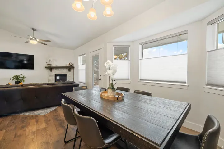 Wood-finish flooring throughout, a vaulted ceiling, and a fireplace with a stone surround