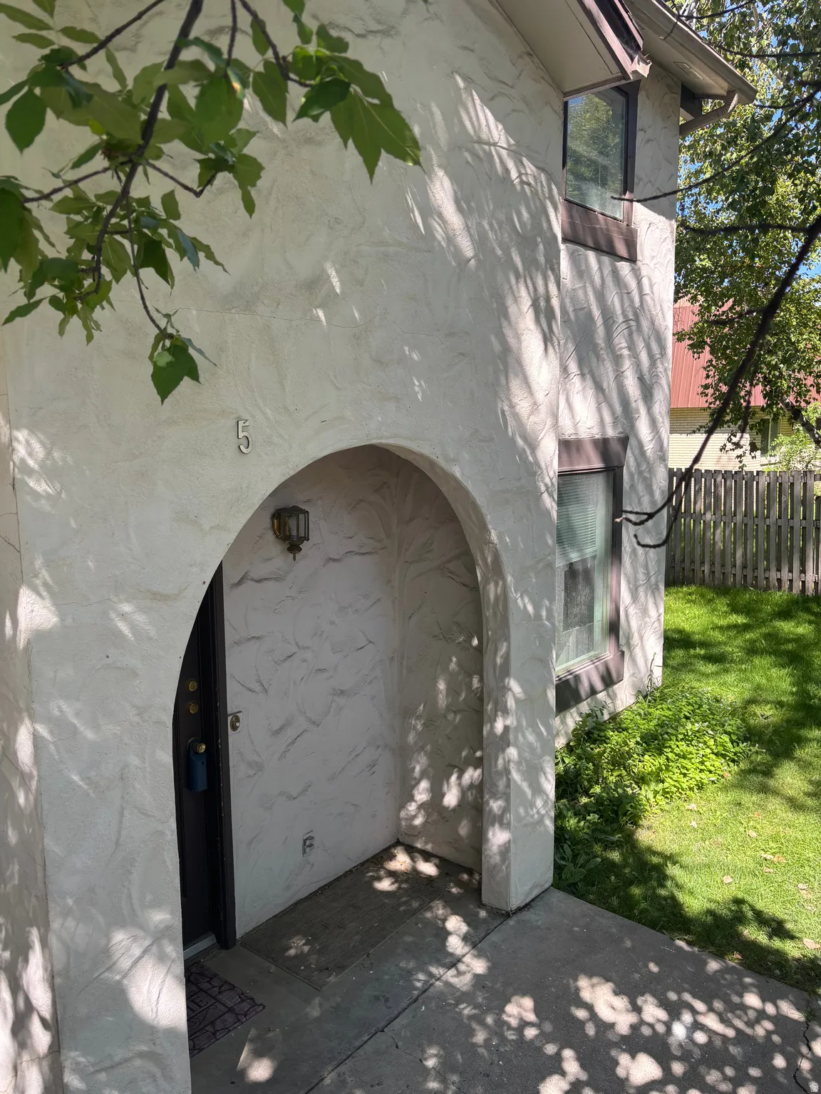 Charming arched entryway with textured stucco exterior and dark wood door