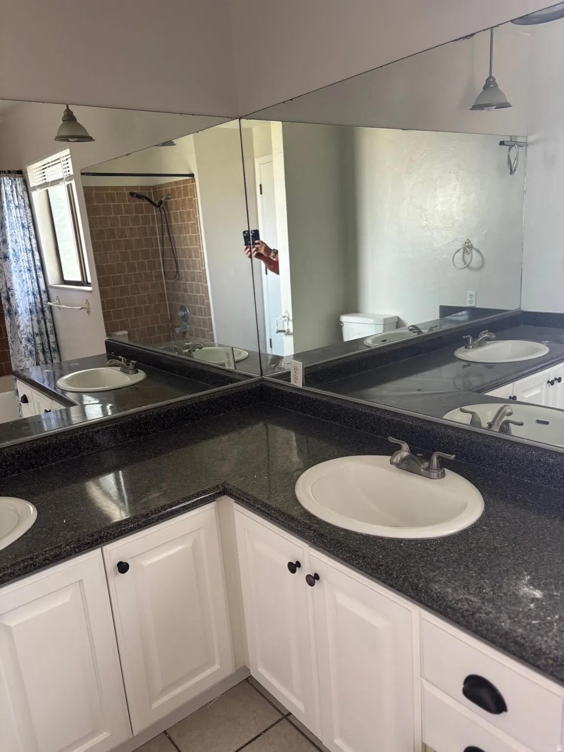 Dual vanity with built-in sinks, dark speckled countertops, white cabinetry, and full-wall mirrors