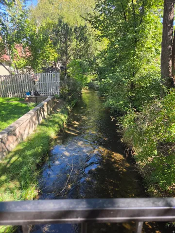 Creek-side property featuring mature trees and a picket fence