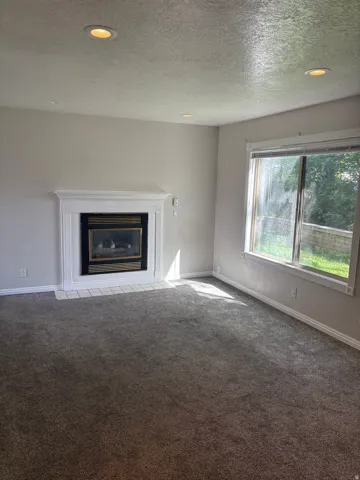 Recessed ceiling lighting illuminates the room featuring a white fireplace mantel and a dark insert