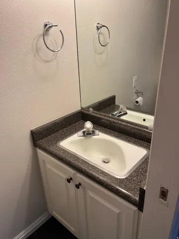 Vanity with an integrated sink, dark speckled countertop, and white cabinet storage