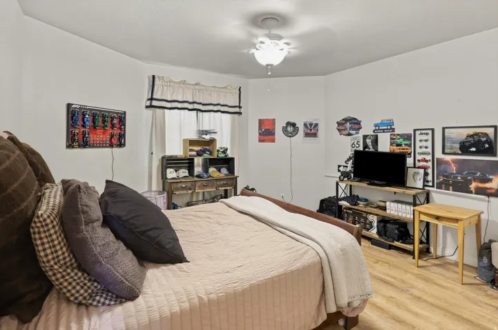 Wood-finish flooring, white walls, and a ceiling fan with integrated lighting