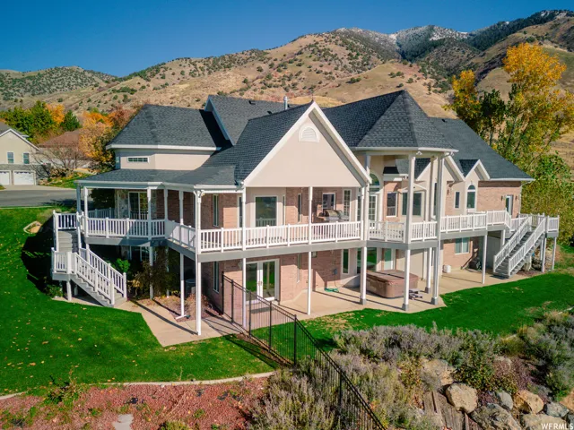 Multi-level exterior featuring brick siding, multiple covered decks, and white railings