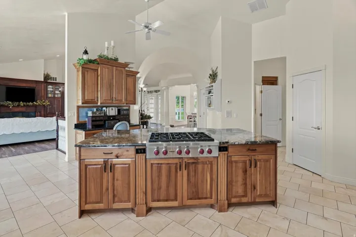 Kitchen island with integrated range, natural wood cabinetry, and stone-finish countertops