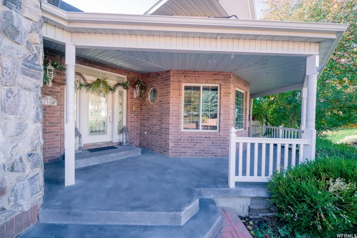 Brick exterior with stone accents, a covered porch, white baluster railing, and a bay window