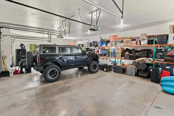 Concrete flooring in a spacious garage with permanent overhead track lighting and built-in wall shelving