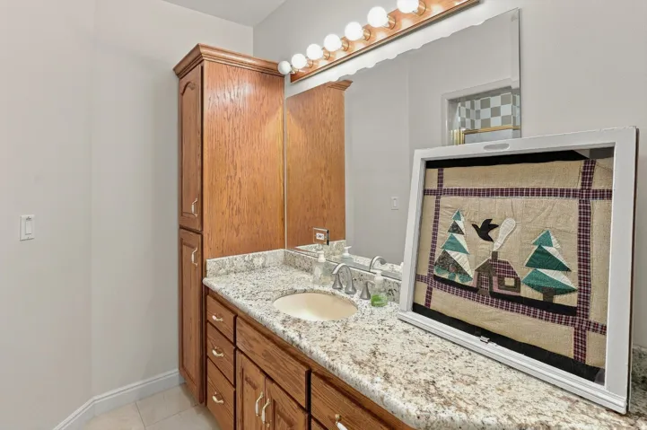 Wood-finish vanity with an integrated sink, polished chrome faucet, and speckled countertop