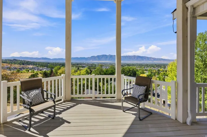 Expansive outdoor deck with a mountain backdrop, featuring white balusters and columns, and composite decking