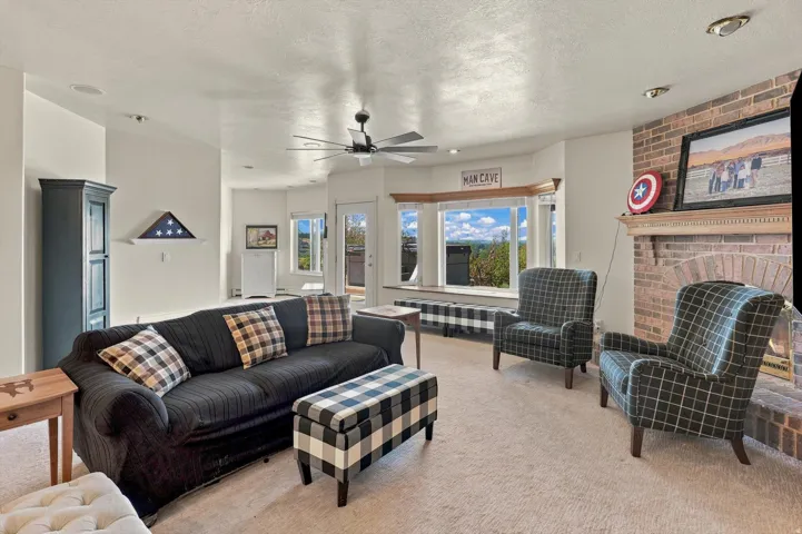 Living area featuring a brick fireplace, built-in window seating, and a ceiling fan