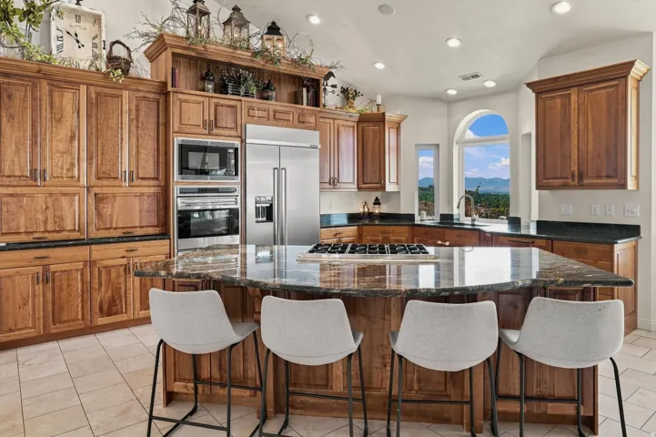 Spacious kitchen with wood cabinetry, stainless steel appliances, a large central island, and multiple windows