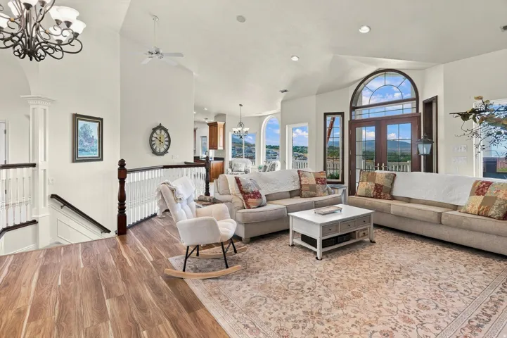 Vaulted ceiling, recessed lighting, wood-finish flooring, decorative staircase balustrade, and arched transom windows