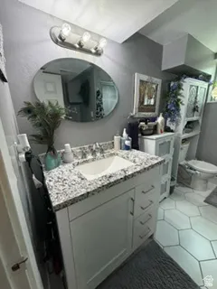 White vanity with an integrated sink, speckled countertop, and brushed nickel hardware