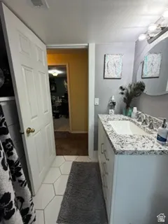 White shaker-style vanity with polished hardware, dual basin sink, and a granite countertop