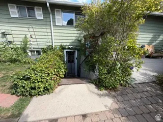 Siding exterior with multiple windows, mature landscaping, and a concrete pathway