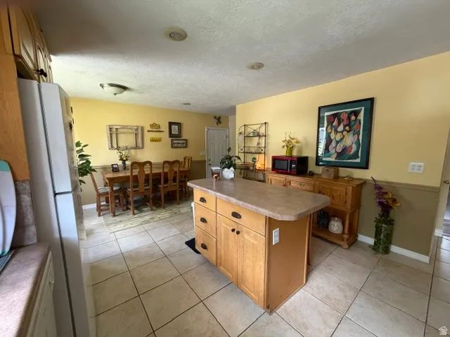 Kitchen featuring a central island with storage, light wood-finish cabinetry, tile flooring, and recessed ceiling lighting