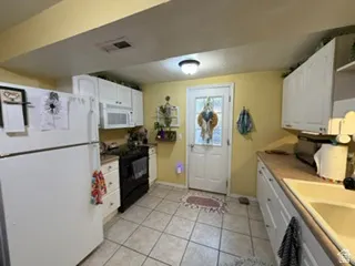 Kitchen featuring white cabinetry, tile flooring, and a rear exterior door with frosted glass