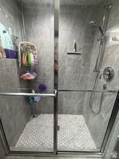Glass-enclosed shower featuring large format wall tiles and a honeycomb mosaic tile floor