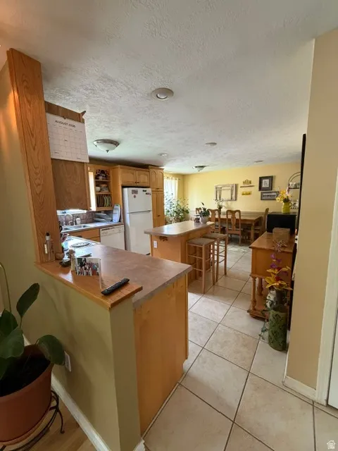 Open-concept living space featuring a kitchen, dining area, and neutral tile flooring