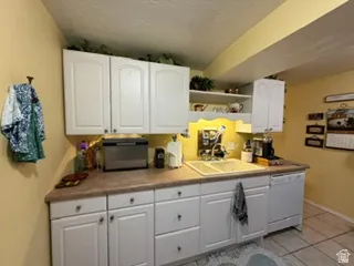 White cabinetry, dual-basin sink, laminate countertops, and a built-in dishwasher