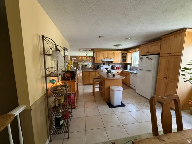 Kitchen featuring light wood-finish cabinetry, a central island, and tile flooring