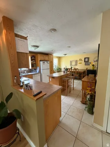Open-concept living space featuring a kitchen, dining area, and neutral tile flooring