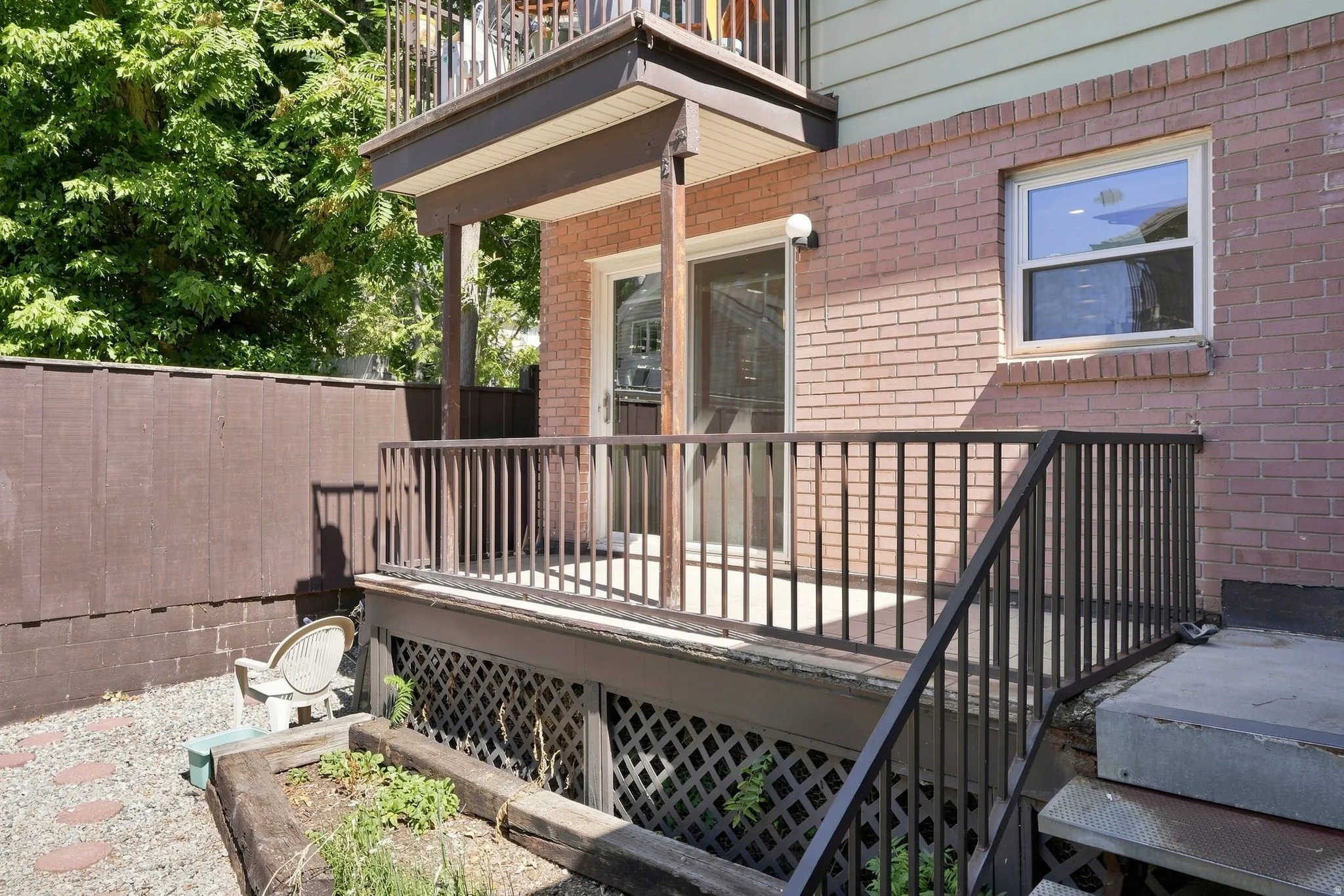 Lower-level patio with brick exterior and privacy fencing