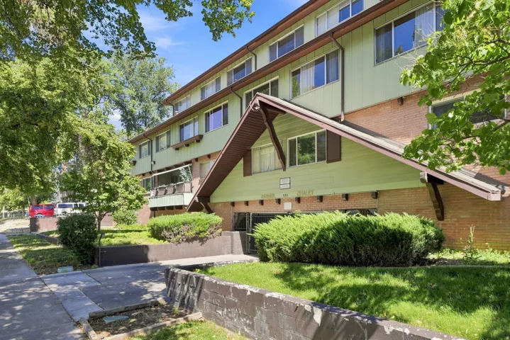 Multi-story building featuring brick and horizontal siding, with a covered entryway and mature landscaping