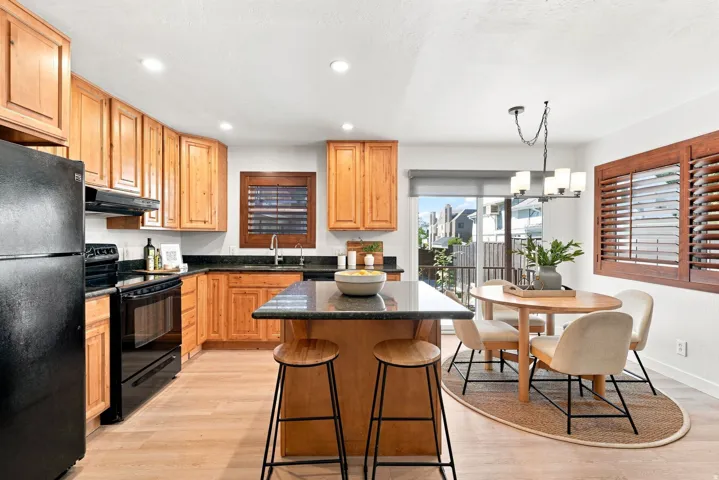 Kitchen featuring wood cabinetry, dark countertops, wood-finish flooring, recessed lighting, and a sliding glass door