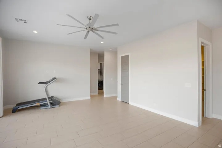 Spacious room featuring light-toned flooring, recessed lighting, and a contemporary ceiling fan