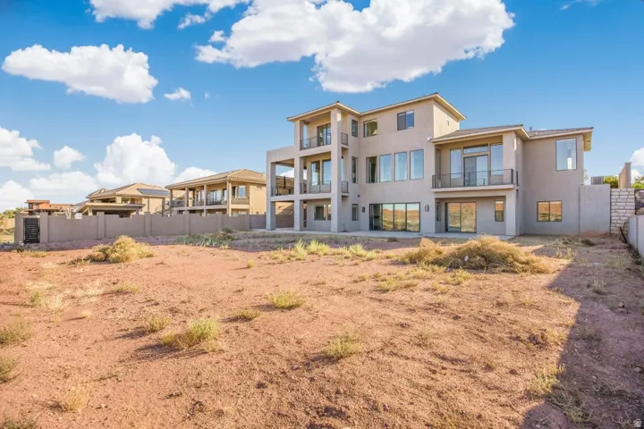 Stucco exterior with multiple balconies, expansive windows, and a sliding glass door