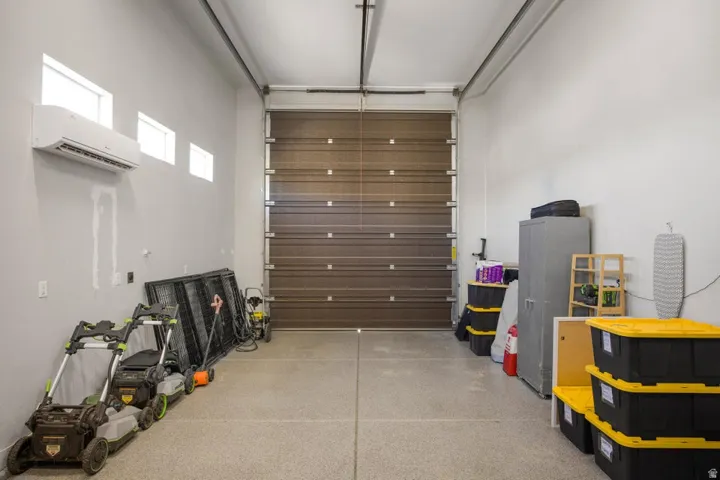 Garage featuring a high ceiling, a brown paneled garage door, an installed air conditioning unit, and multiple transom windows