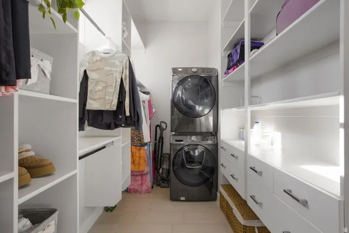 Custom built-in white shelving, integrated drawers with metal hardware, light-toned flooring, and a stacked washer and dryer unit