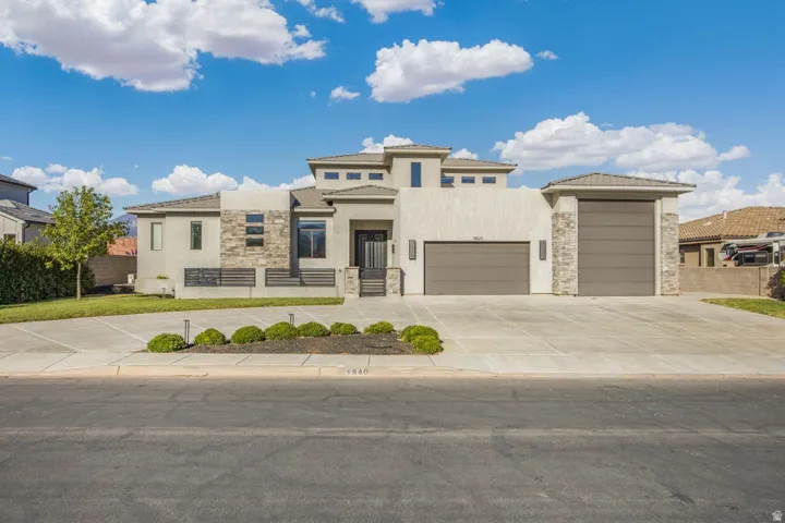 Contemporary exterior design with stucco and stone accents, concrete driveway, and integrated two-car garage