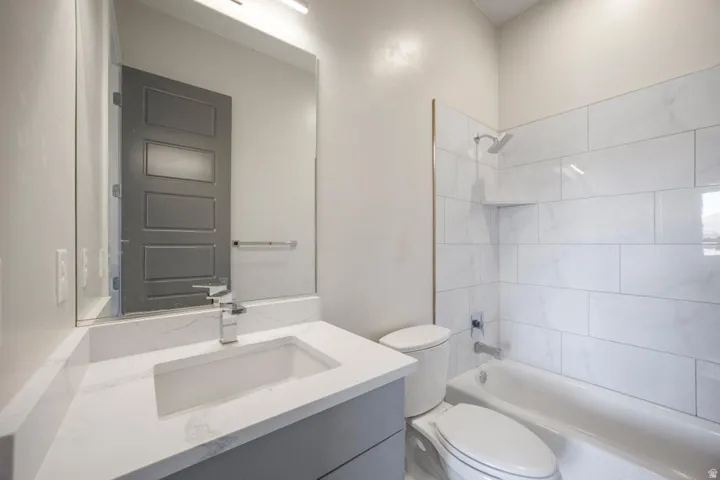 Modern bathroom featuring a single vanity with a white countertop and undermount sink, chrome faucet, and a tub/shower combination with white subway tile surround