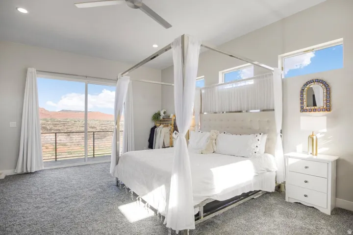 Sliding glass door leading to an outdoor balcony with metal railing, high ceilings, transom windows, and a ceiling fan