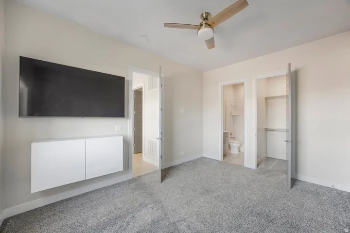 Plush gray carpeting throughout, featuring a ceiling fan, and two integrated closet spaces