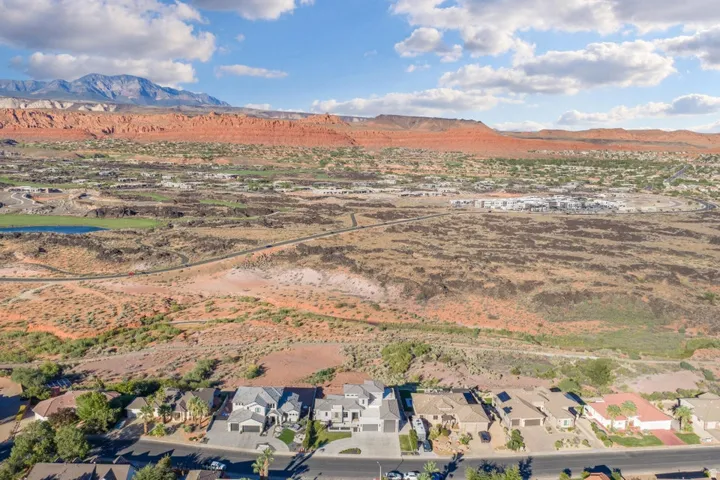 Expansive desert landscape with distant mountains, featuring a residential community with varied architectural styles