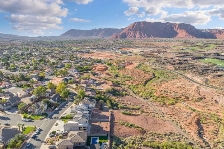 Residential neighborhood with mature trees, surrounded by arid landscape and distant mountains